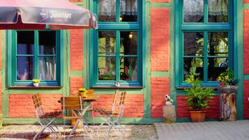 A red brick building with green window frames and a table with chairs outside.
