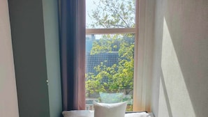 A neatly made bed with white linens and towels, a radiator, and a window with curtains. - The Flying Pig Uptown Hostel (Amsterdam)