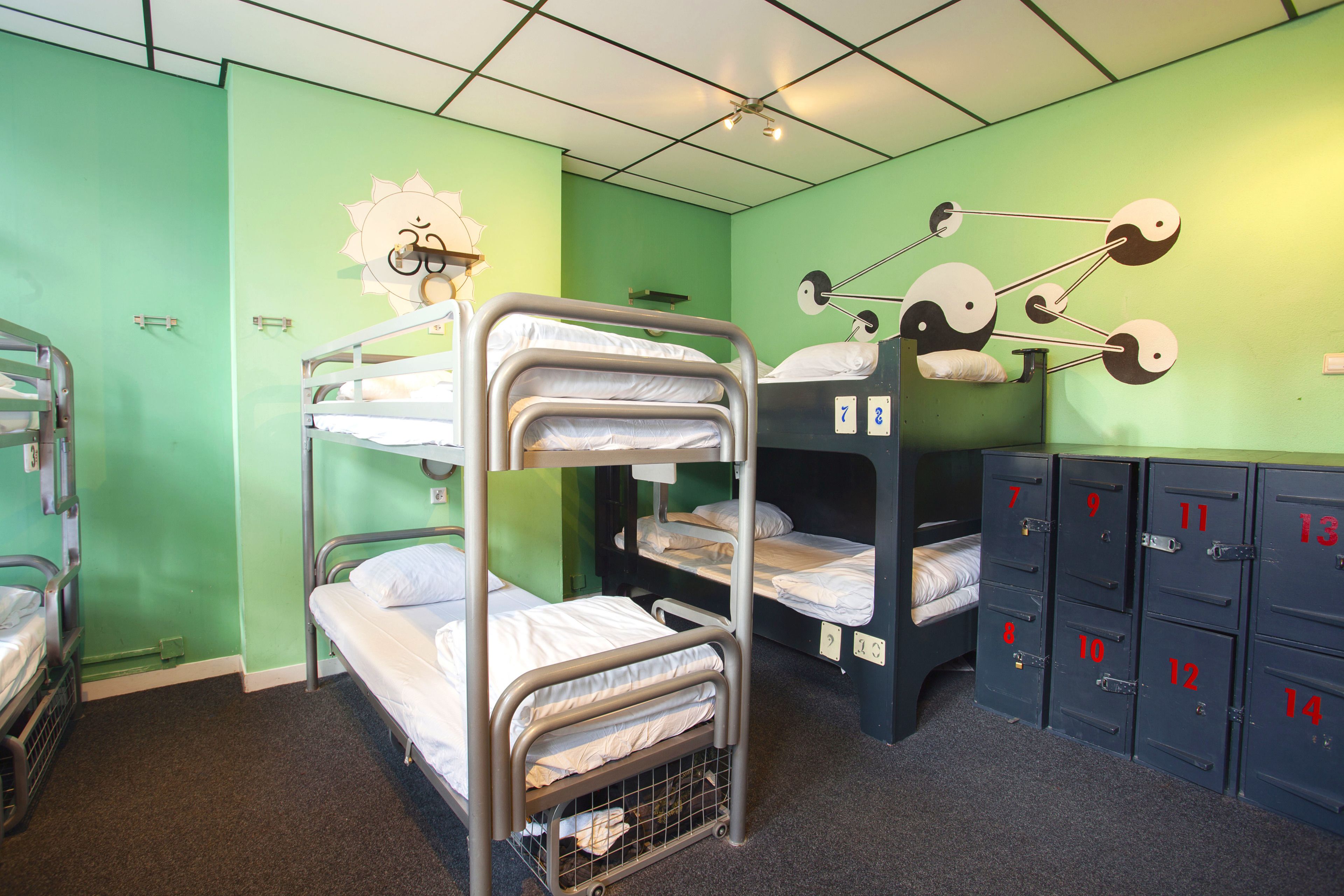 Un dormitorio con literas, una bicicleta estática fijada a la pared y taquillas numeradas.