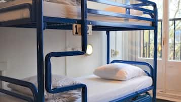 A bunk bed with a pull-out desk and a window with a view of trees.