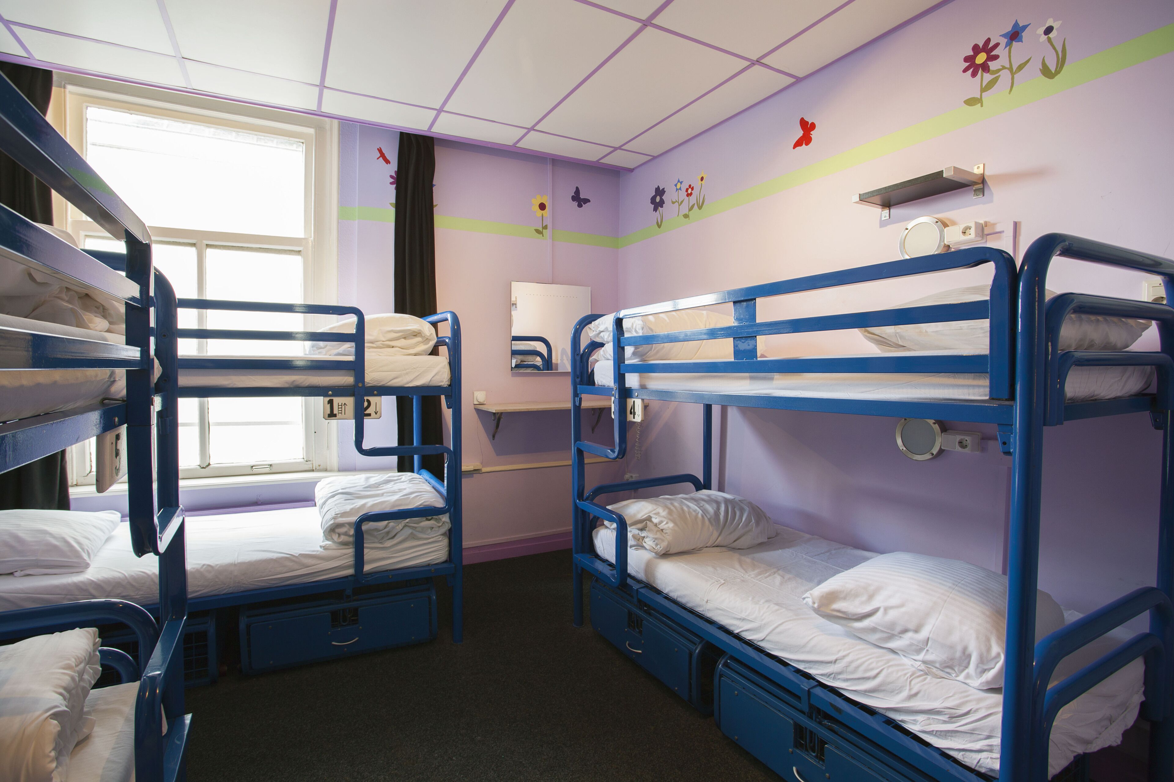 Una habitación tipo dormitorio con literas, una ventana, un espejo y un adorno en la pared.