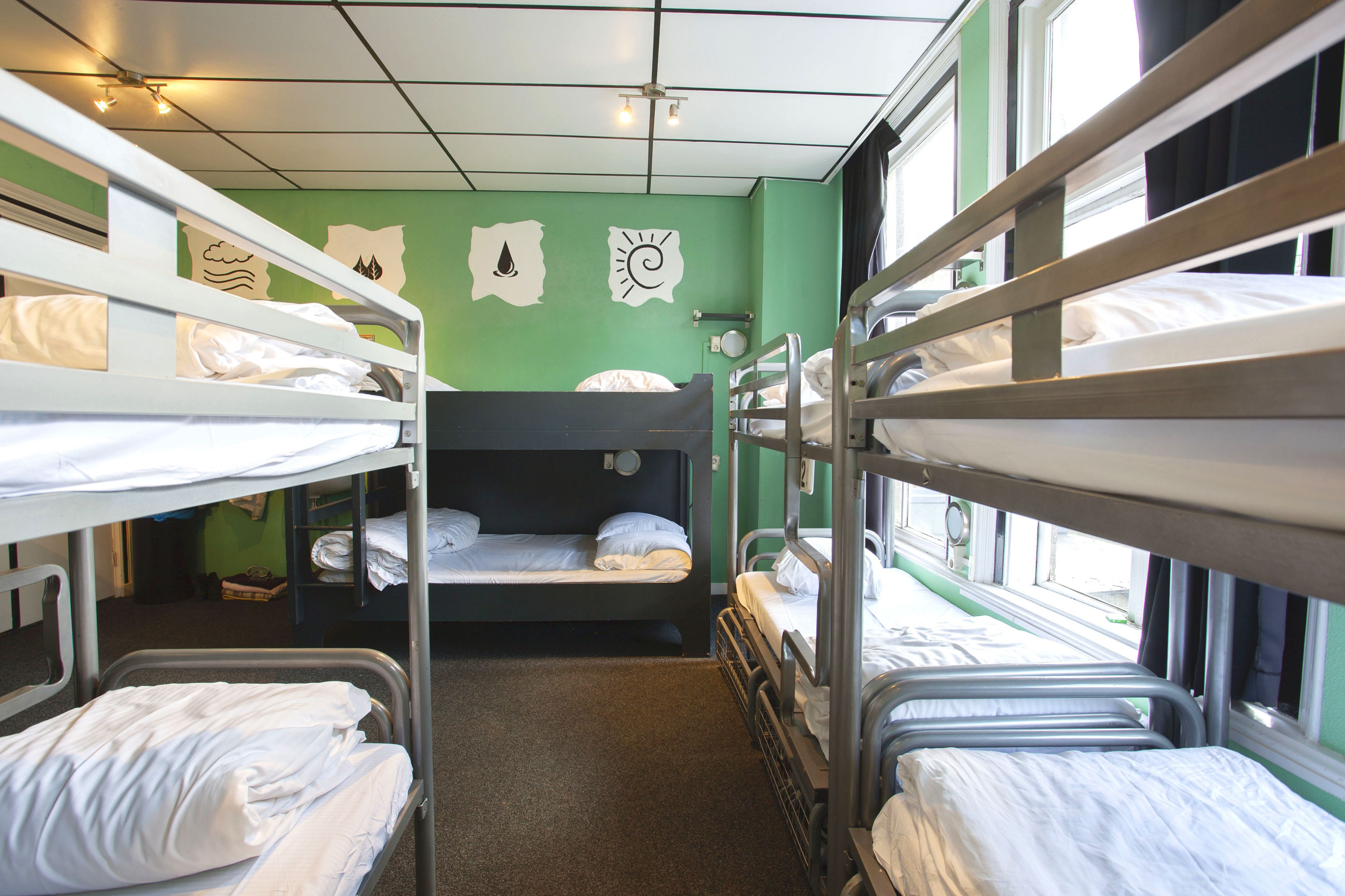 Un dormitorio con literas, una pared verde y una ventana.