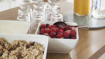 A breakfast buffet with various food items including granola, berries, and yogurt.