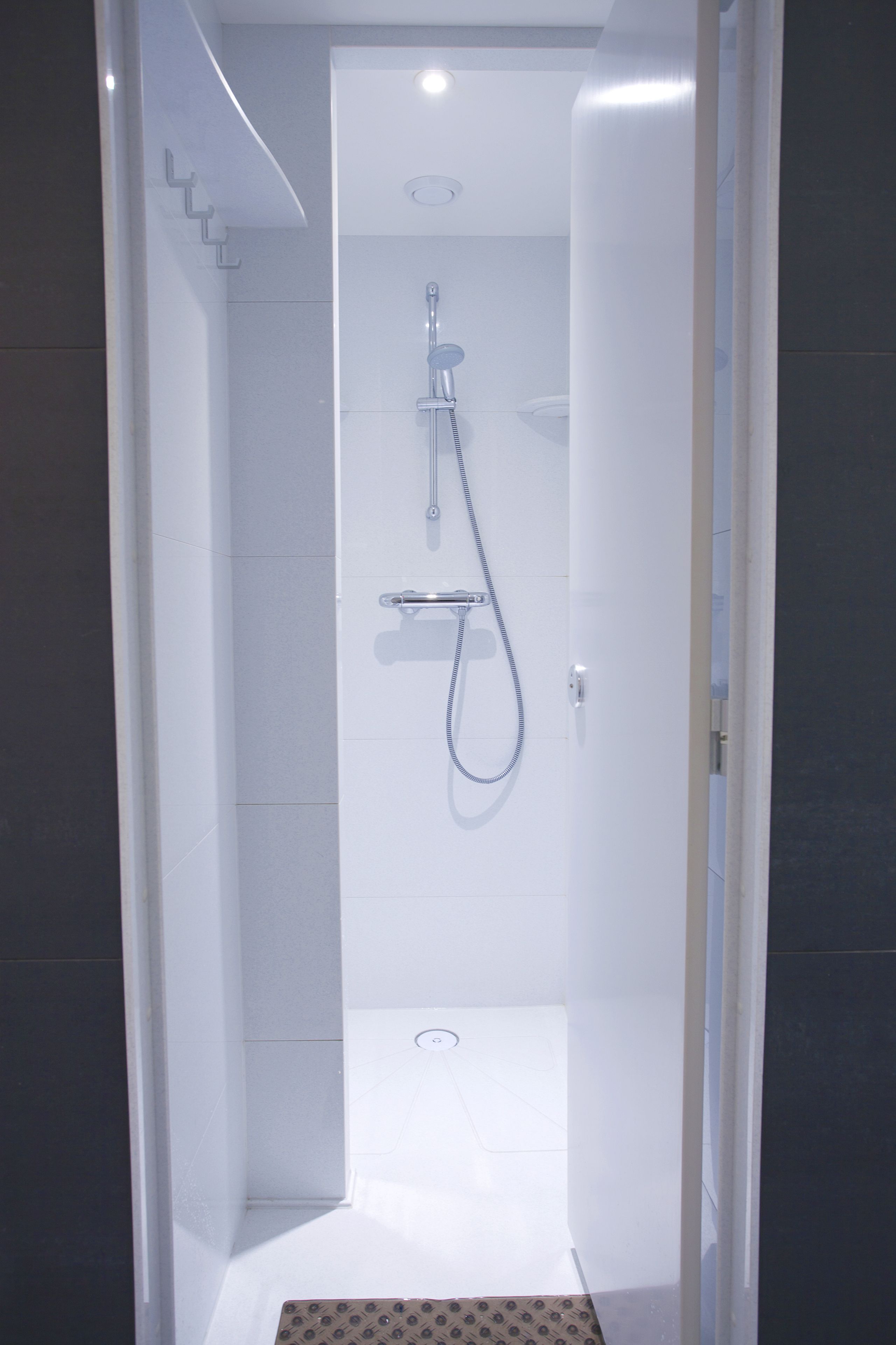 A modern, enclosed shower area with a handheld showerhead and a wall-mounted faucet.