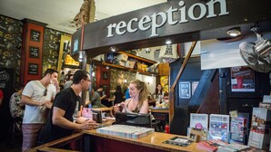 Un espace d’accueil avec un panneau au-dessus du comptoir, un ventilateur et divers affiches d’information.