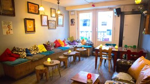 Un salon chaleureux avec un canapé, des fauteuils et des tables, dont les murs sont ornés de tableaux encadrés.