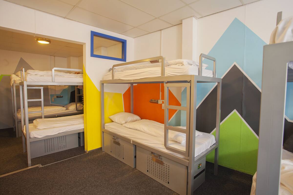 Een slaapzaal met stapelbedden, een spiegel en geometrische wanddecoraties.