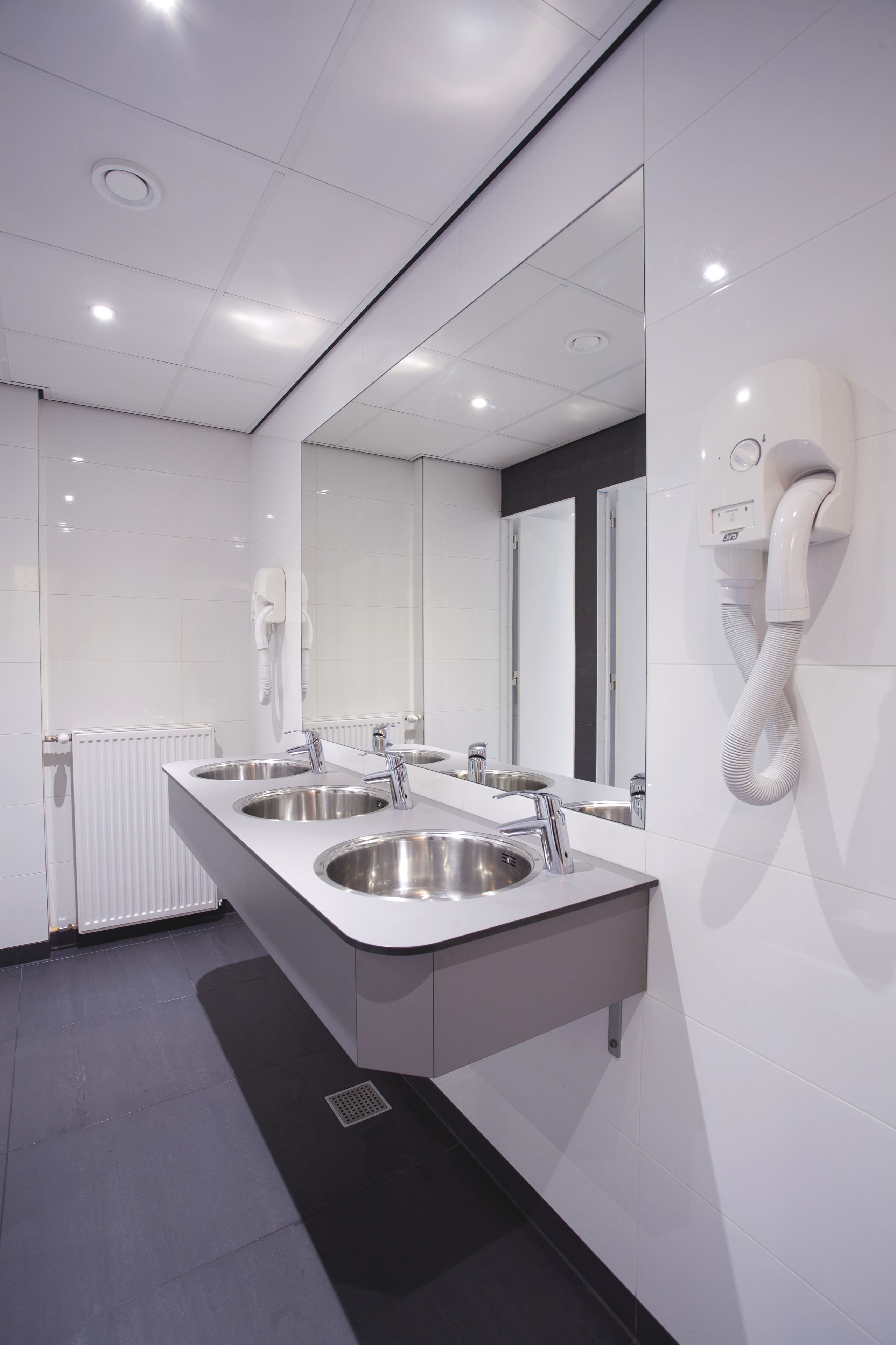 Un bagno moderno con due lavabi, uno specchio grande e un telefono fissato alla parete.