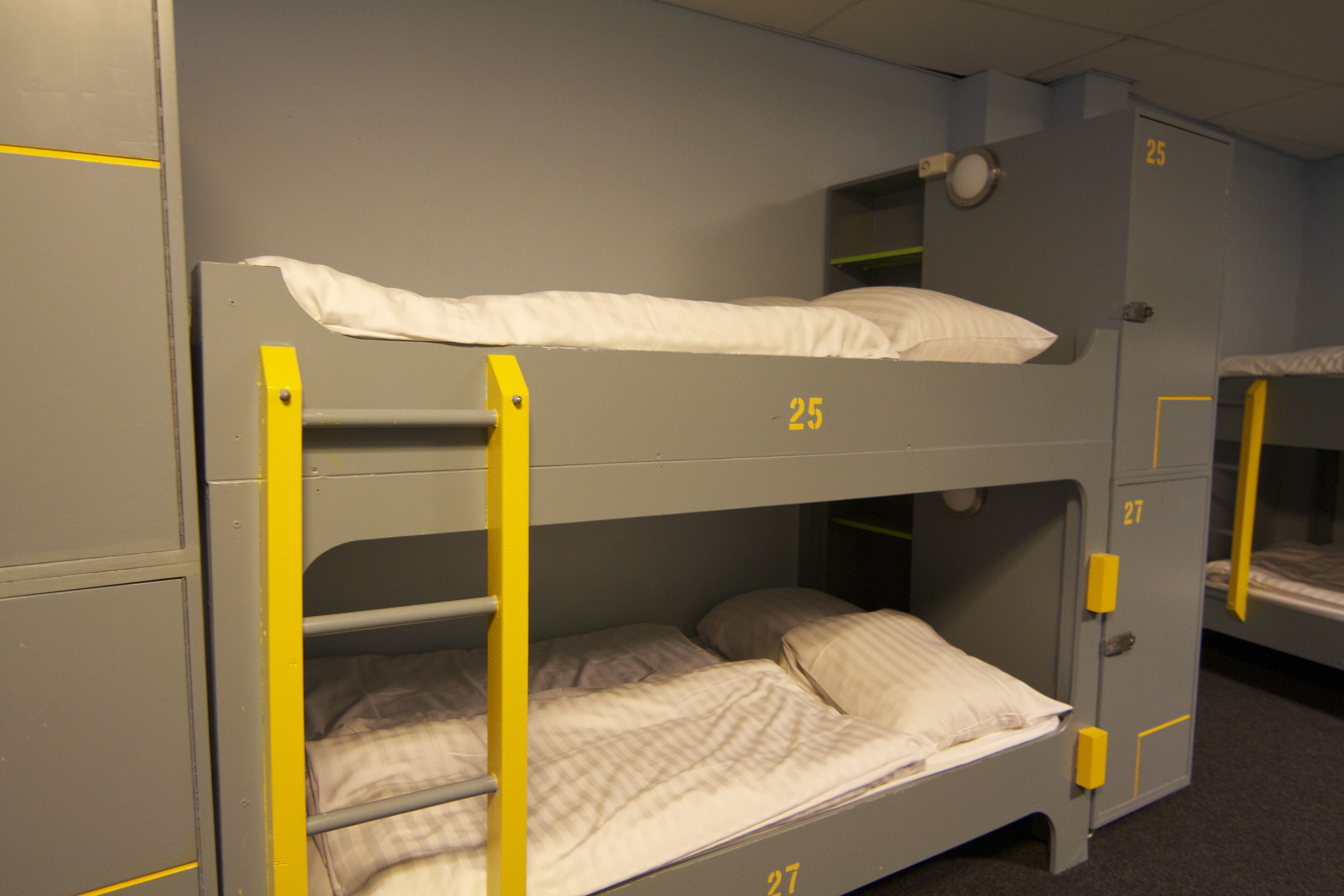 A bunk bed room with numbers 25 and 27 on the walls, indicating room numbers.
