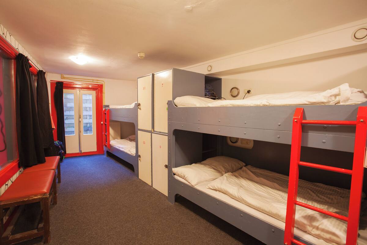 Een slaapzaal met stapelbedden, een bureau en een kledingkast.