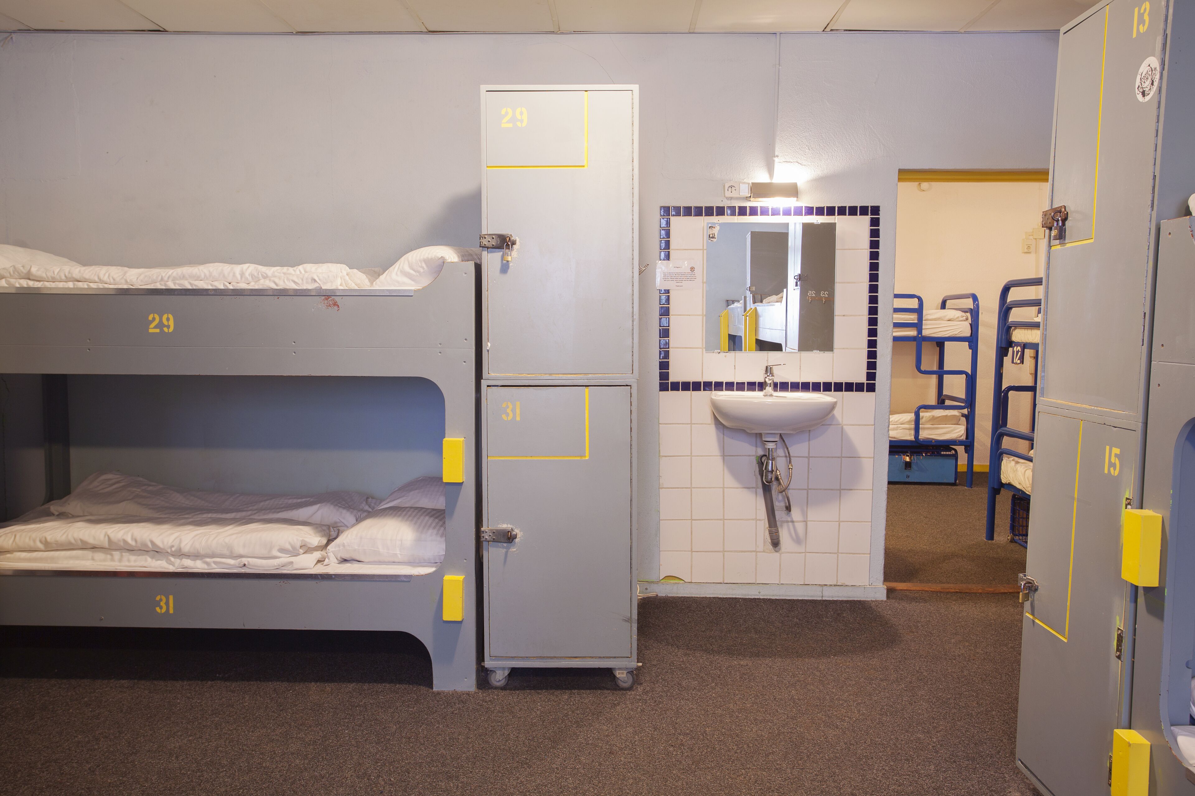 Una camera del dormitorio con letti a castello, un angolo cottura, un lavandino e uno specchio.