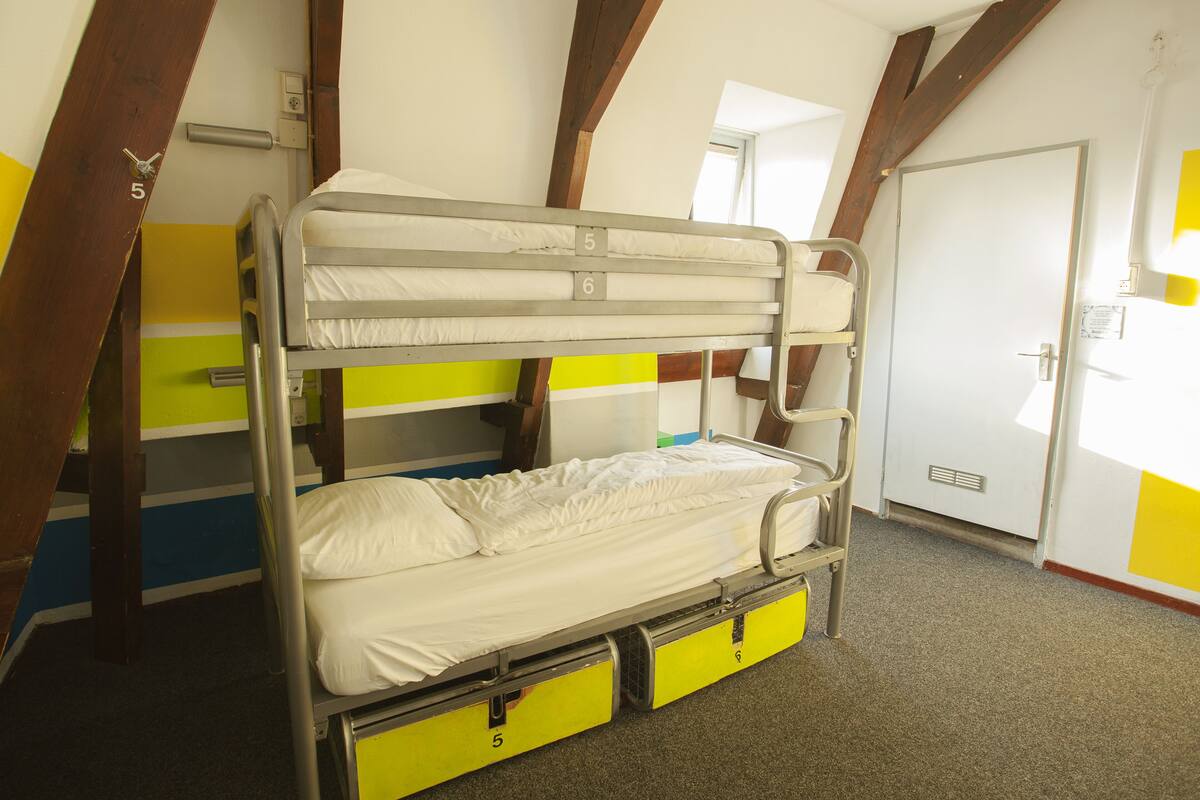 Een stapelbed met een onderbed, een deur en een raam.