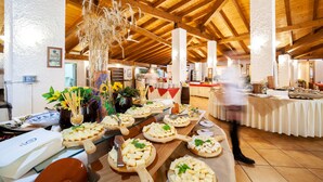 A buffet setup with various food items and a person in the background. - TH Gioiosa Marea - Capo Calavà Village (Gioiosa Marea)