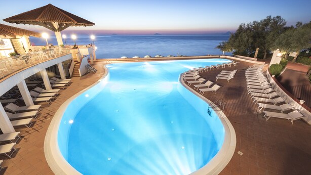 A swimming pool with a view of the sea, sun loungers, and a covered area with umbrellas. - TH Gioiosa Marea - Capo Calavà Village (Gioiosa Marea)