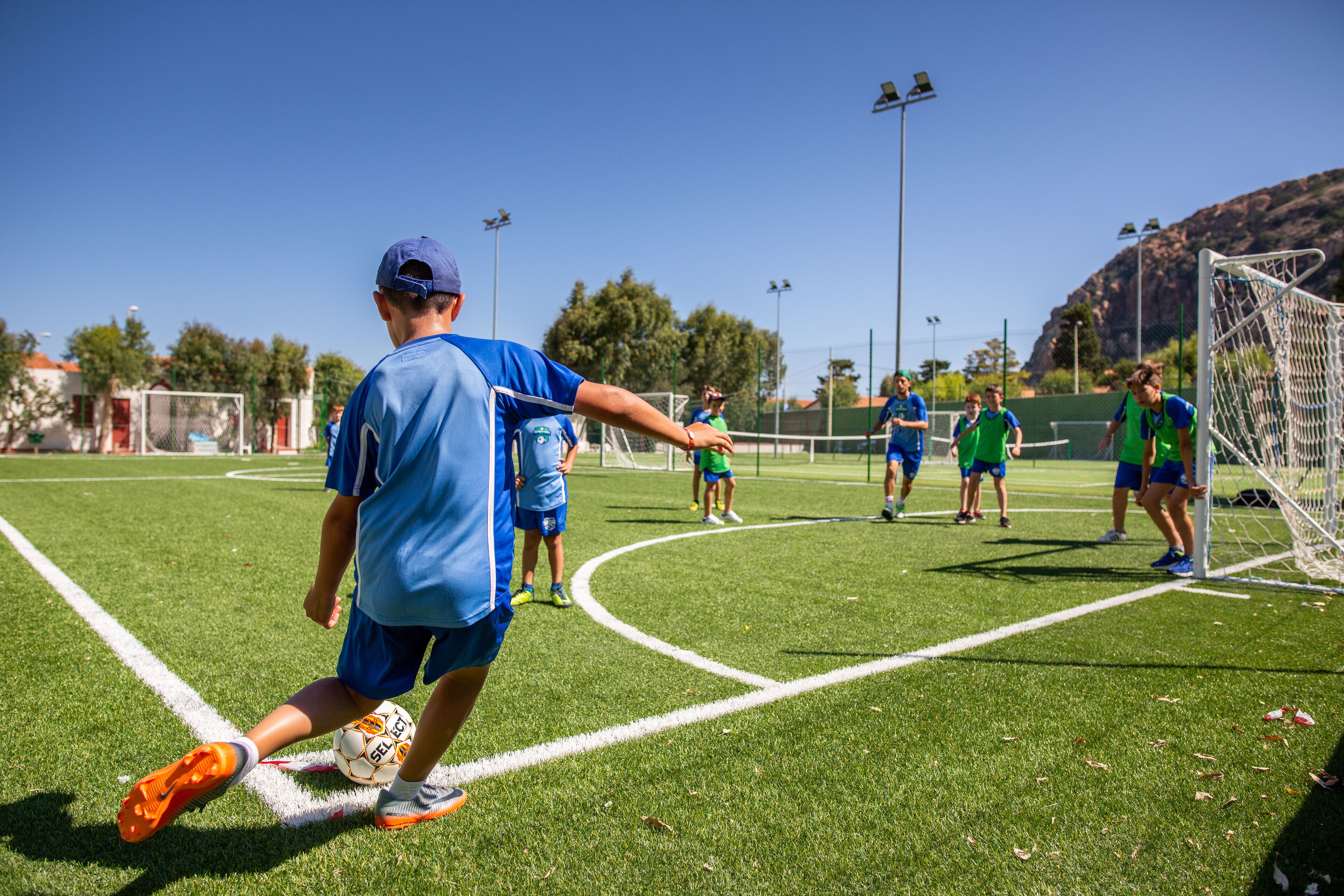 Un campo de fútbol con jugadores uniformados en azul y verde.