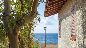 A coastal building with a wooden balcony overlooking the sea, a lamp post, and a view of the ocean. - TH Gioiosa Marea - Capo Calavà Village (Gioiosa Marea)