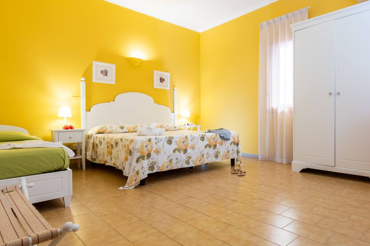 A bedroom with a bed, nightstands, a wardrobe, and a window with curtains.