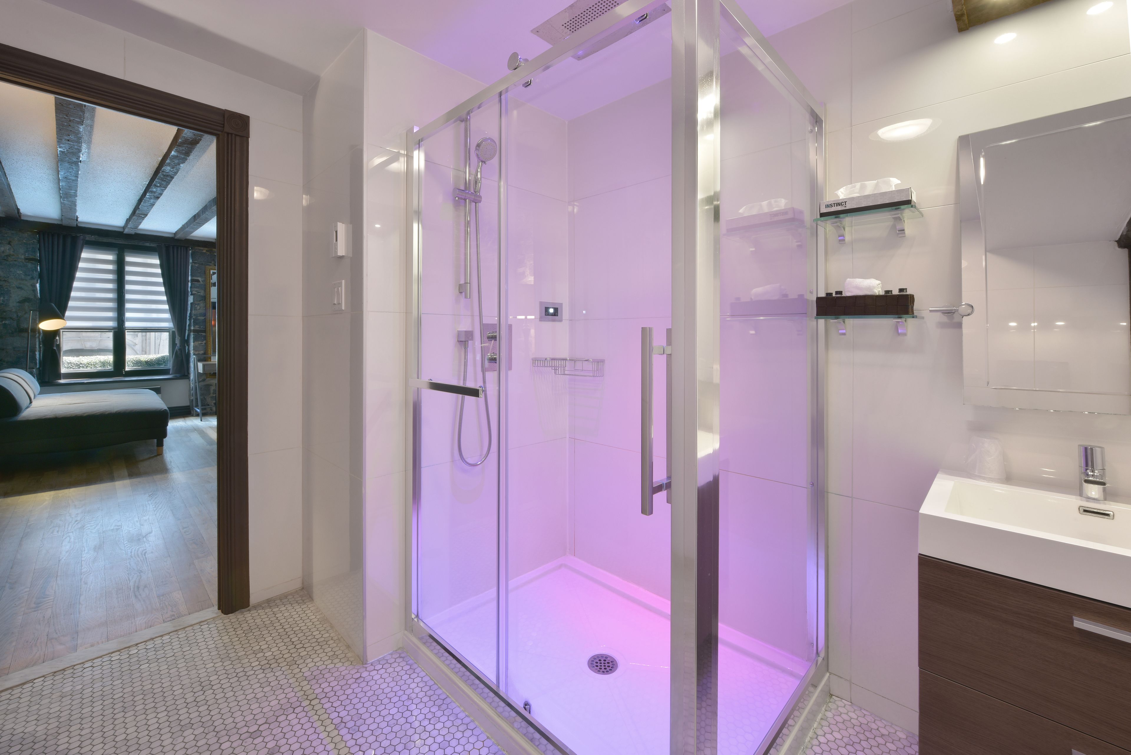 A modern bathroom with a glass-enclosed shower, a white sink, and a mirror.