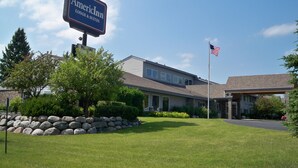 A building with a sign reading "American Inn LODGE & SUITES" and an American flag.
