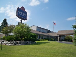 A building with a sign reading "American Inn LODGE & SUITES" and an American flag.