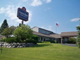 Un edificio con un letrero que dice "American Inn LODGE & SUITES" y una bandera estadounidense.