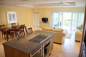 A modern kitchen with granite countertops, a built-in oven, and a dining area with wooden chairs.