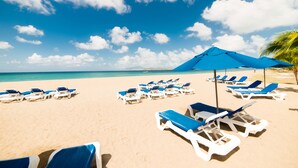 A beach with rows of blue and white sun loungers and a blue umbrella. - The Hamilton Beach Villas & Spa (Cotton Ground)