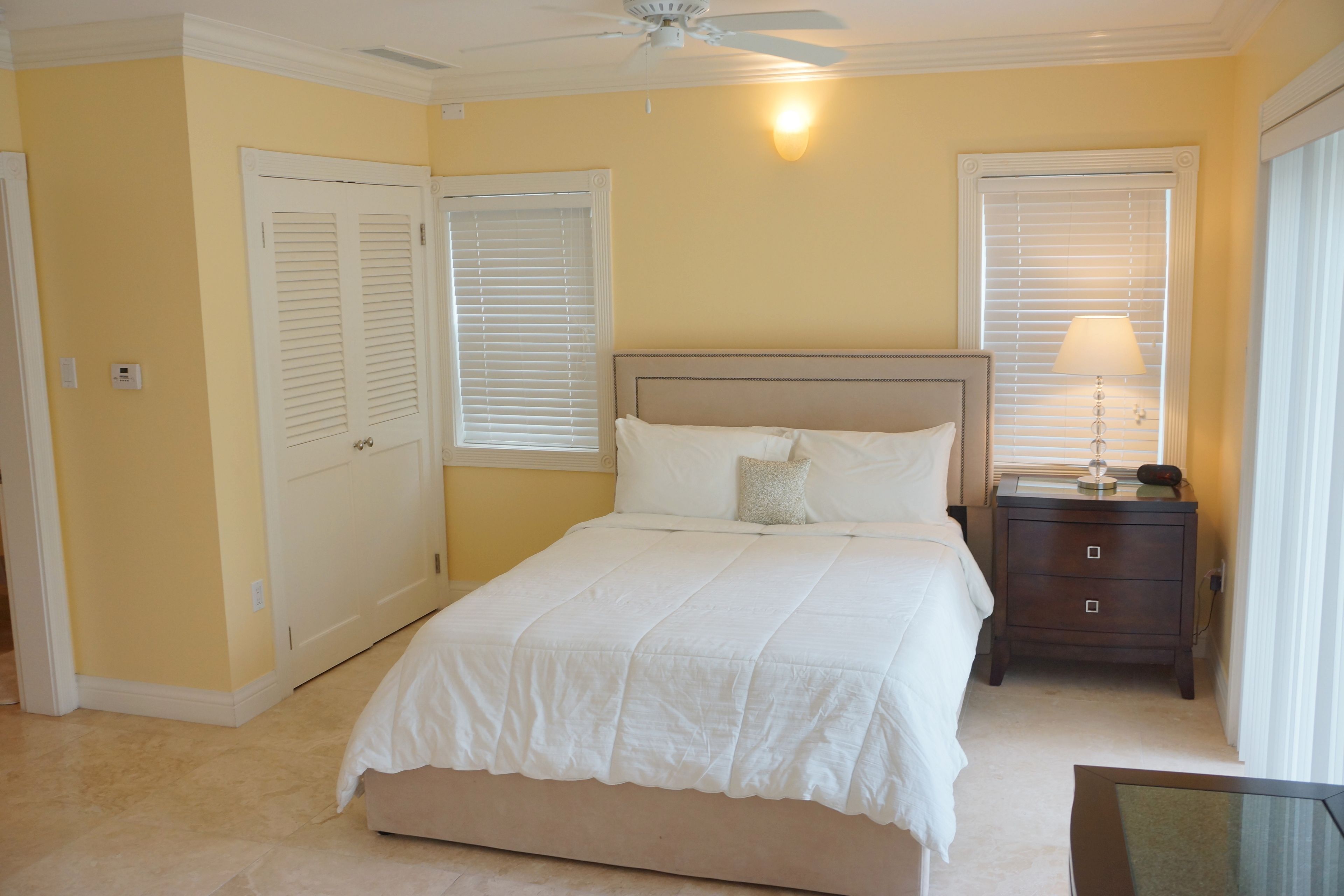 A bedroom with a bed, a nightstand, a lamp, and a ceiling fan.