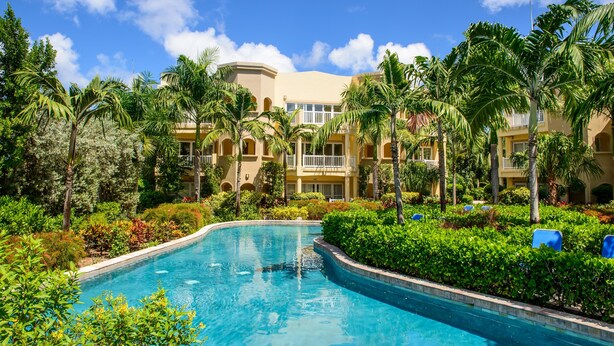 A resort with a swimming pool surrounded by lush greenery and palm trees. - The Hamilton Beach Villas & Spa (Cotton Ground)