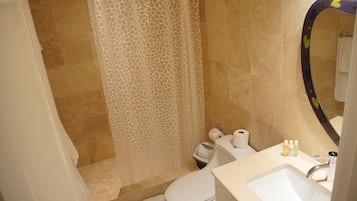 Une salle de bain équipée d’une douche, de toilettes, d’un lavabo et d’un miroir orné d’un motif en forme de cœur.