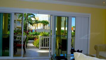A hotel room with a sliding glass door leading to a balcony with a view of a pool and palm trees.