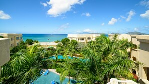 A resort with a pool surrounded by palm trees, a beach view, and a clear blue sky. - The Hamilton Beach Villas & Spa (Cotton Ground)