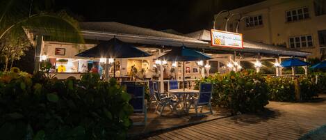 A beachfront restaurant with outdoor seating and umbrellas.