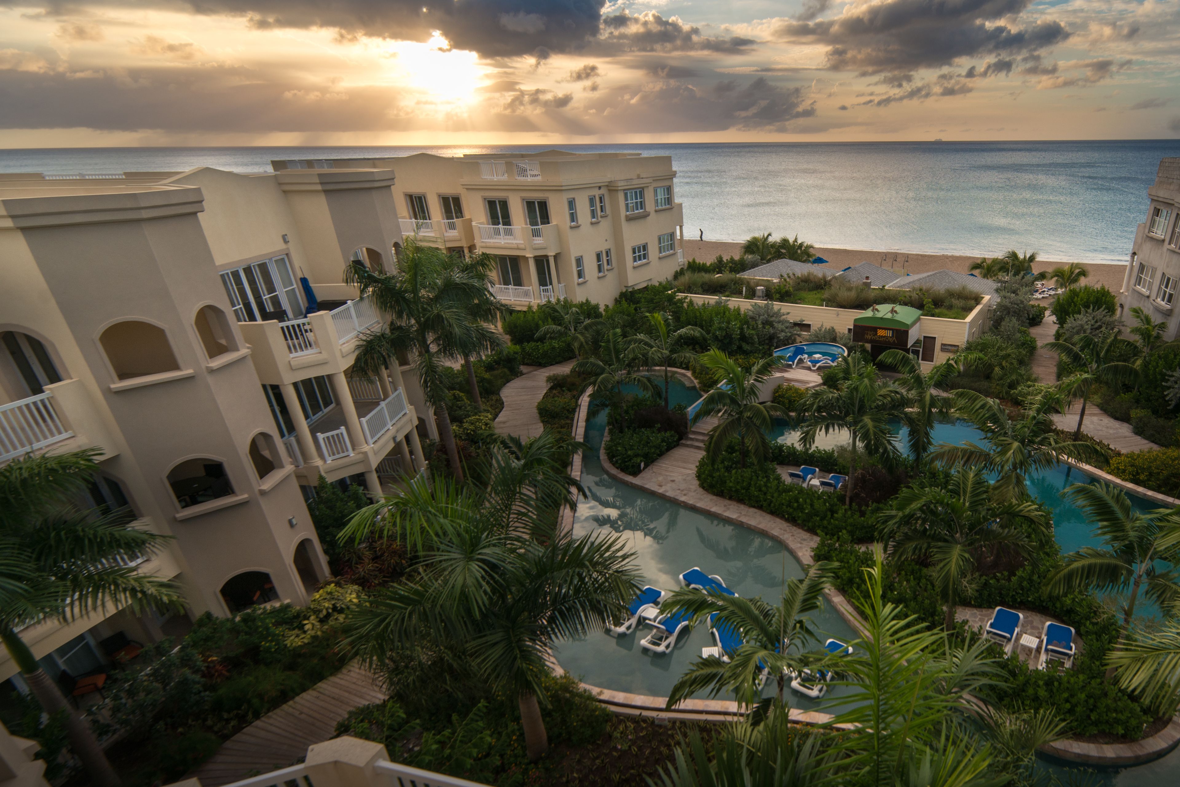 Un resort con piscina, palmeras y vista al océano.