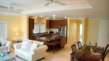 A spacious living area with a white sofa, a glass coffee table, and a dining table set for six.
