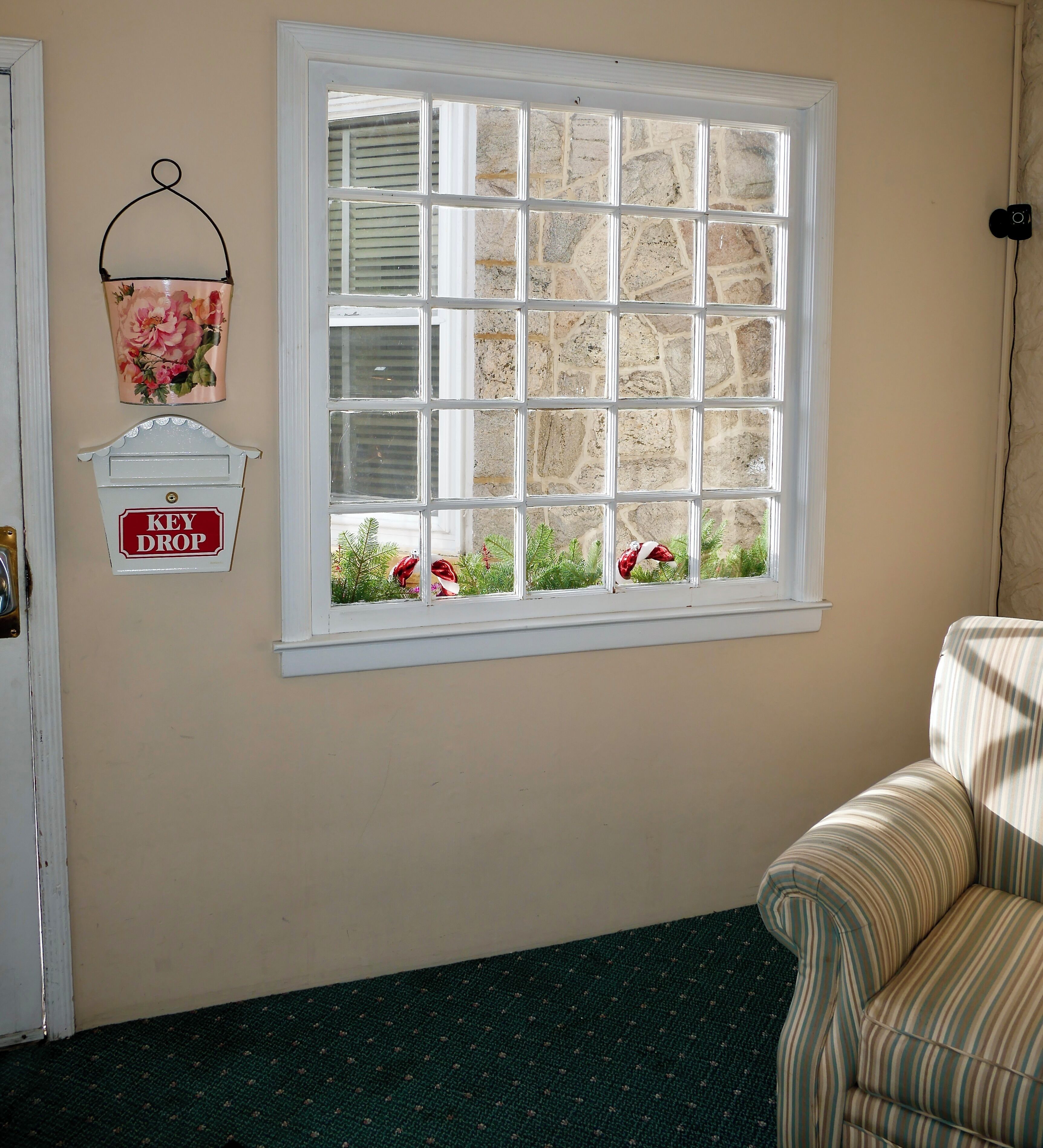 A room with a large window, a key drop, and a striped armchair.