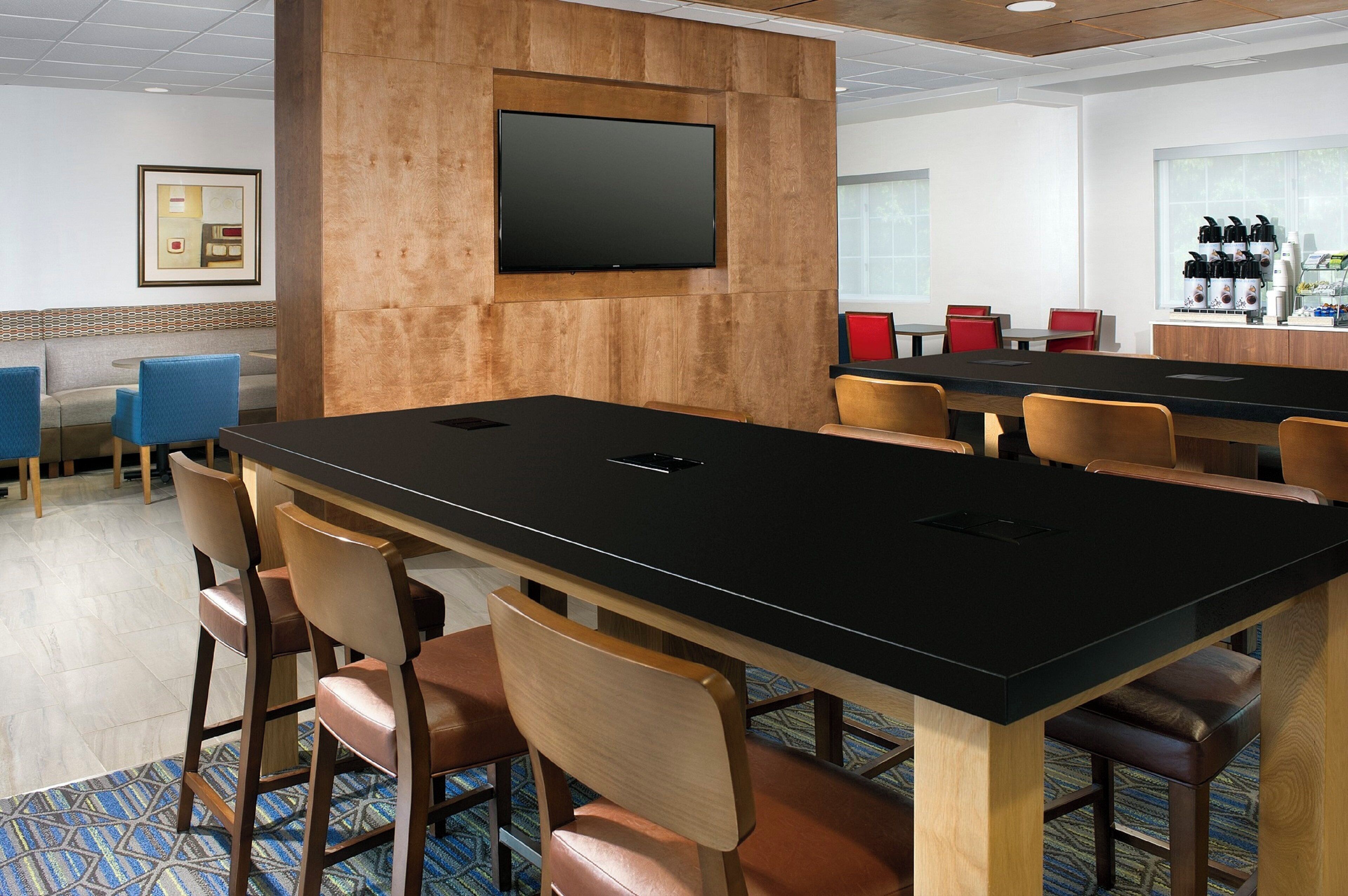 A conference room with a long table, chairs, a television, and a coffee station.