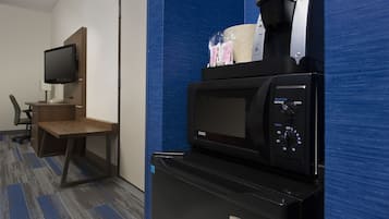 A hotel room with a kitchenette featuring a coffee maker, microwave, and refrigerator.