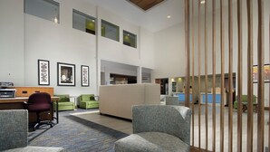 A spacious lobby with seating areas, a reception desk, and framed artwork on the walls.