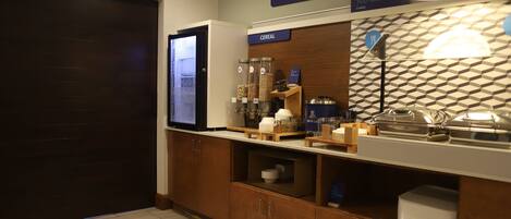 A breakfast area with a cereal dispenser, a microwave, and a sign for Express Start Breakfast.