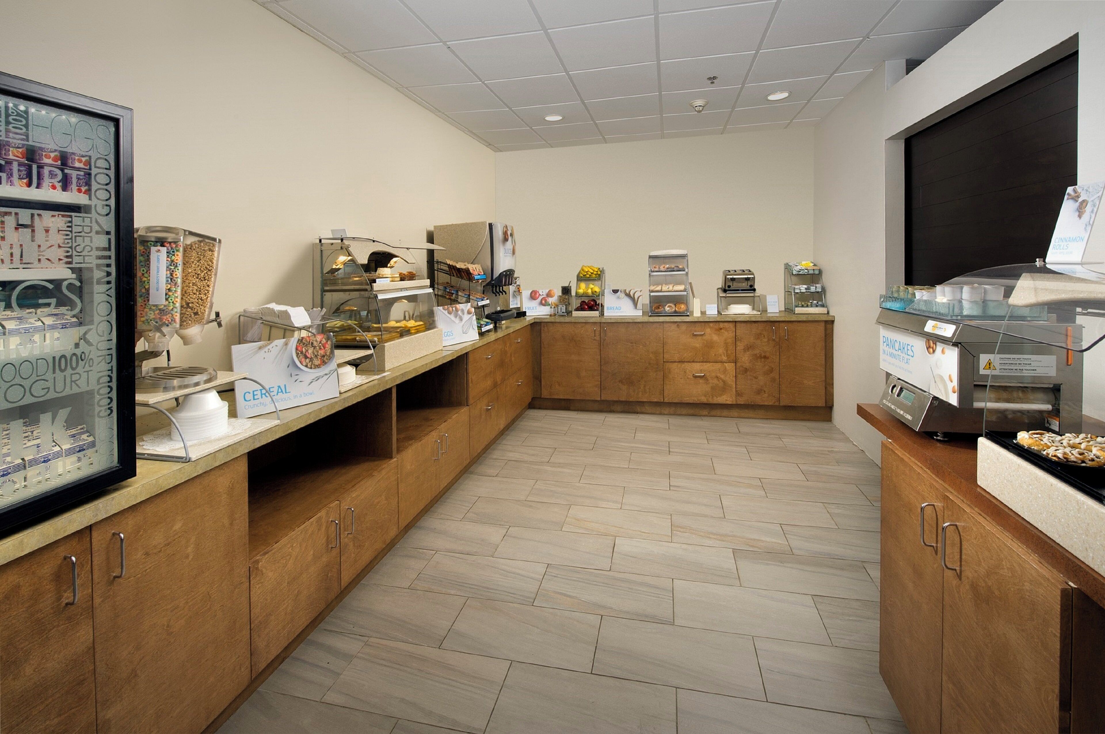 A breakfast buffet area with various food options, including cereal, fruit, and pastries.