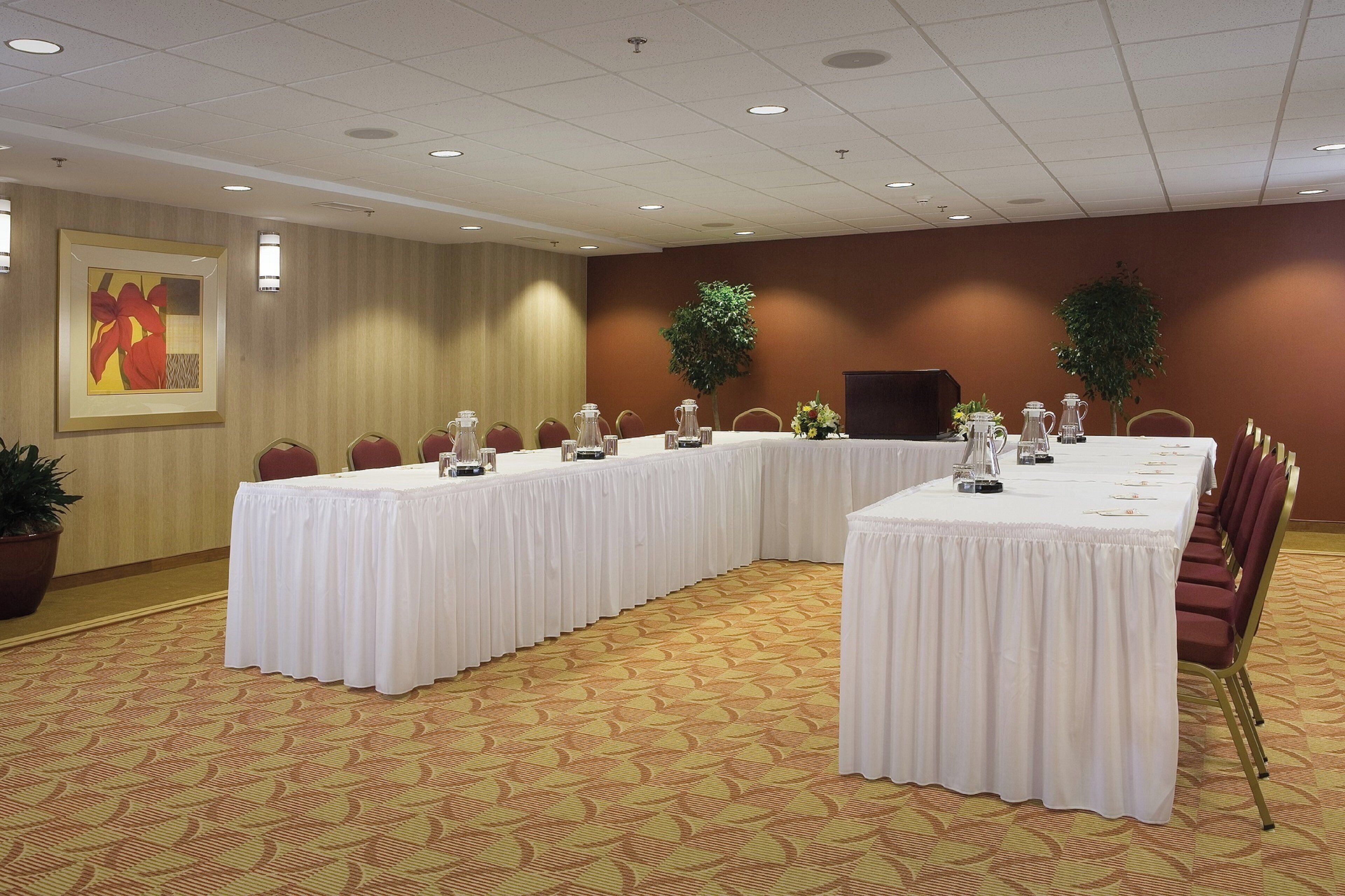 A conference room with a long table, chairs, and a projector screen.