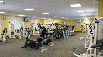 Un gimnasio con equipos de ejercicio variados, incluyendo cintas de correr, elípticas y máquinas de pesas.