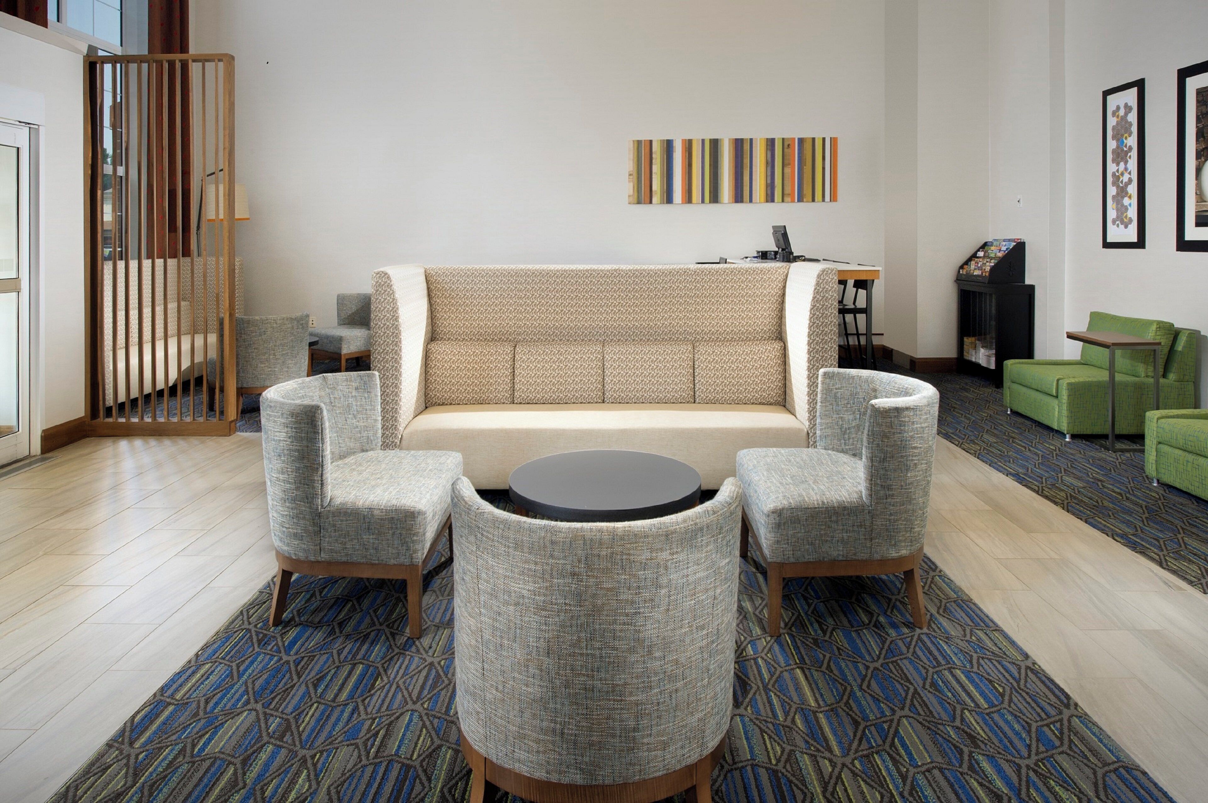 Una sala moderna con un sofá, dos sillones, una mesa de centro y un tapete estampado.