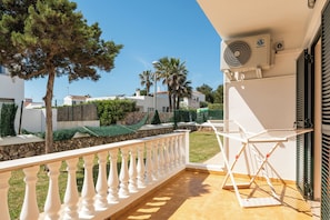 A balcony with a white balustrade, a white folding table, and a ceiling fan.