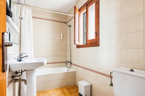 A bathroom with a bathtub, a sink, a toilet, and a shower. - Apartamentos Mar Blanca (Ciutadella de Menorca)