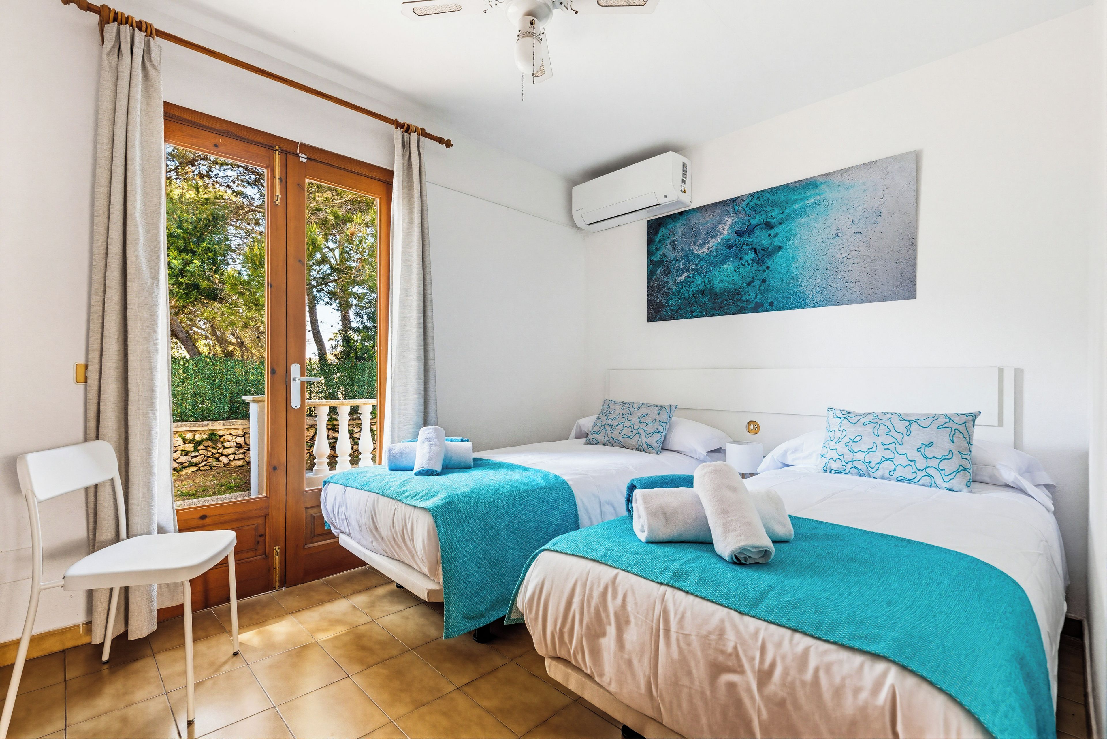 Ein Hotelzimmer mit zwei Betten, Blick ins Freie, einem Gemälde an der Wand und einer Klimaanlage.
