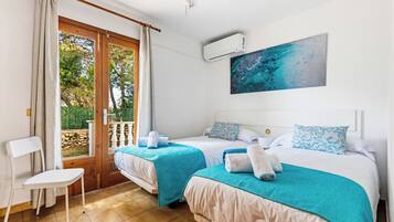 Ein Hotelzimmer mit zwei Betten, Blick ins Freie, einem Gemälde an der Wand und einer Klimaanlage.