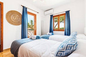 Habitación de hotel con dos camas, un tapiz grande tejido y vistas a zonas verdes.