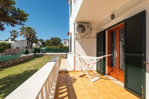 A balcony with a drying rack, a door with shutters, and a clear sky. - Apartamentos Mar Blanca (Ciutadella de Menorca)